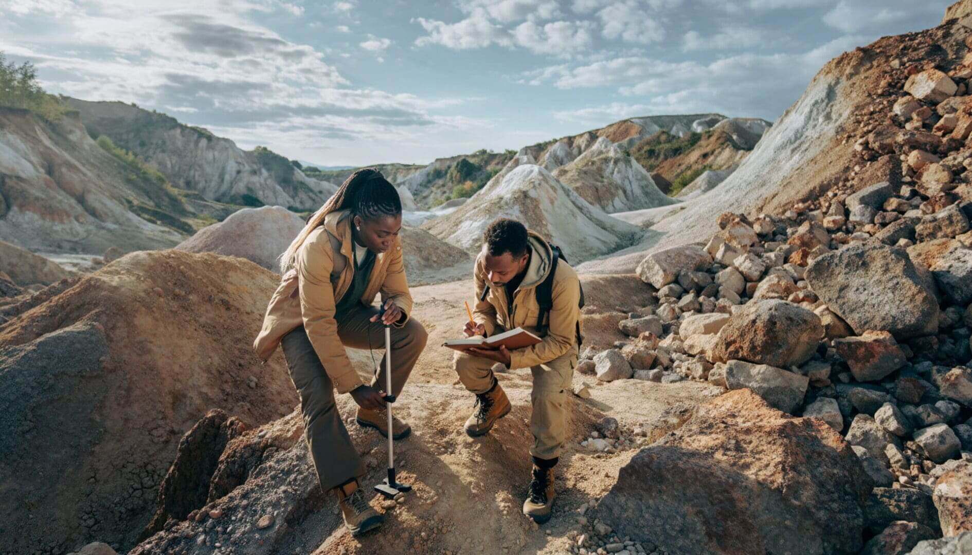 Geologists examining rocky terrain, taking notes.