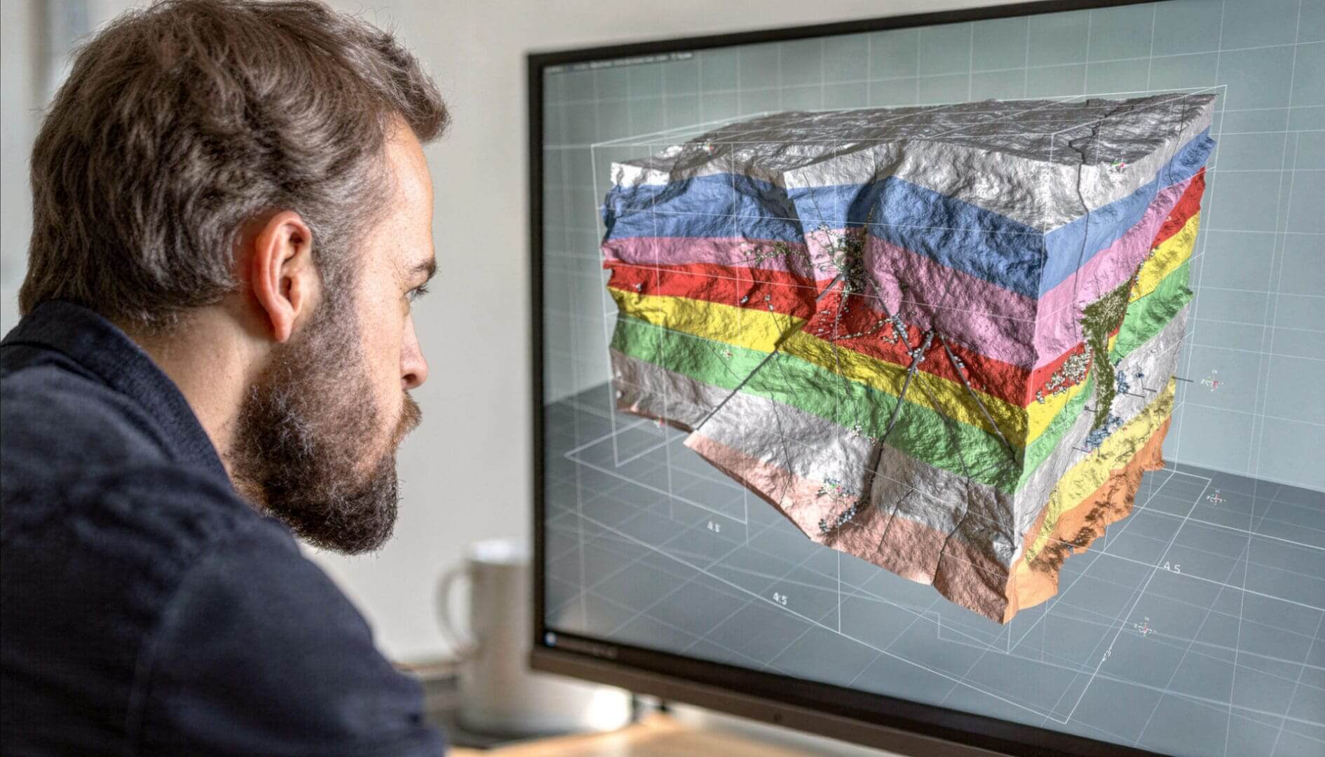 Man analyzing 3D geological model on screen.